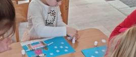 W trakcie warsztatów artystycznych - dzieci kleją obrazy z wycinanek