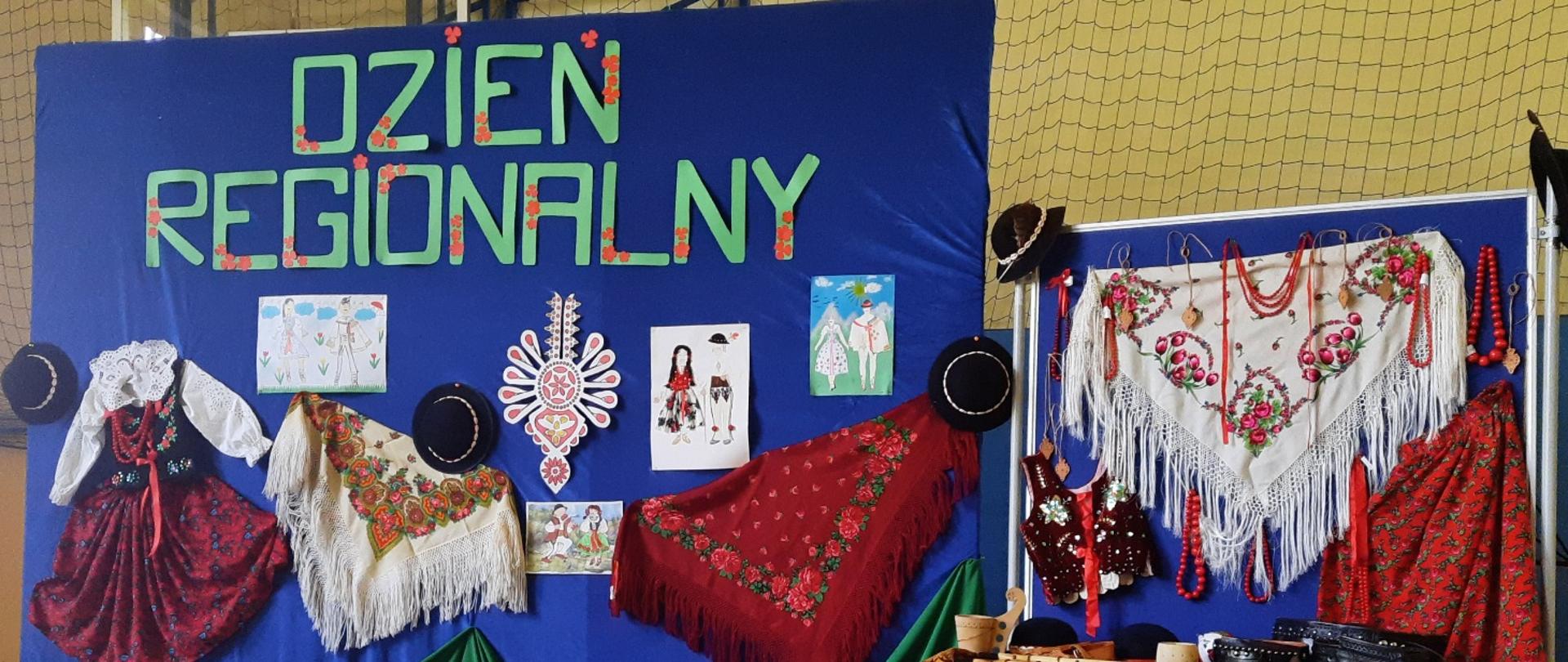 Dzień regionalny w Rokicinach Podhalańskich. Scenografia na sali gimnastycznej z napisem dzień regionalny góralskie chusty, kapelusze, parzenica oraz góralskie obrazki.