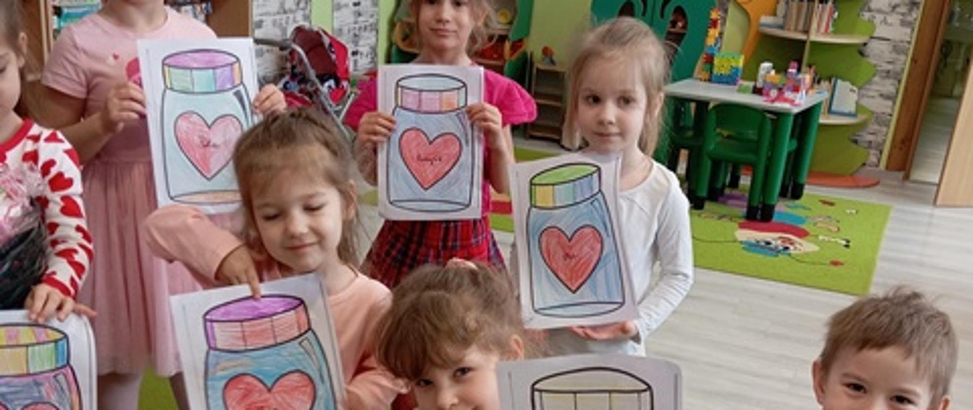 Dzieci pozują do zdjęć trzymając kolorowanki