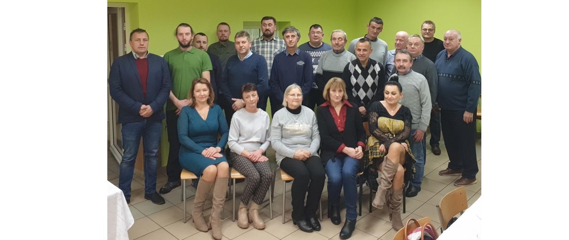 Członkowie Koła Pszczelarzy w Domu Wiejskim w Brzezówce. W pierwszym rzędzie siedzi na krzesłach pięć kobiet. Za nimi stoją mężczyźni.