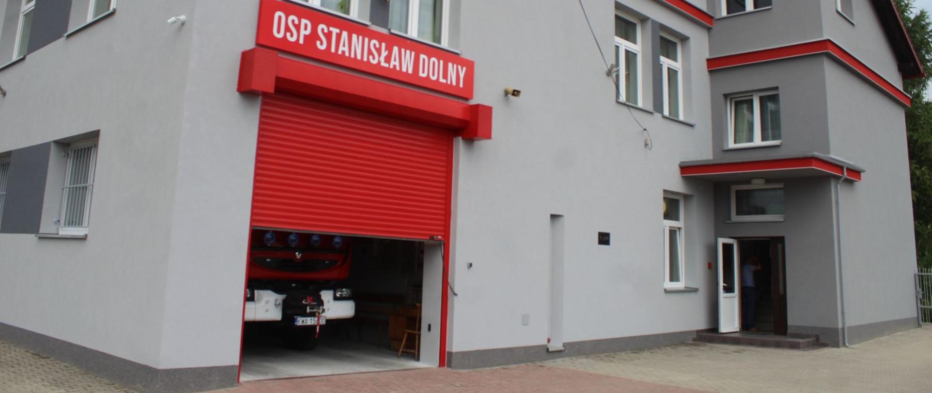 Budynek Ochotniczej Straży Pożarnej, elewacja budynku popielata z czerwonymi dodatkami. 