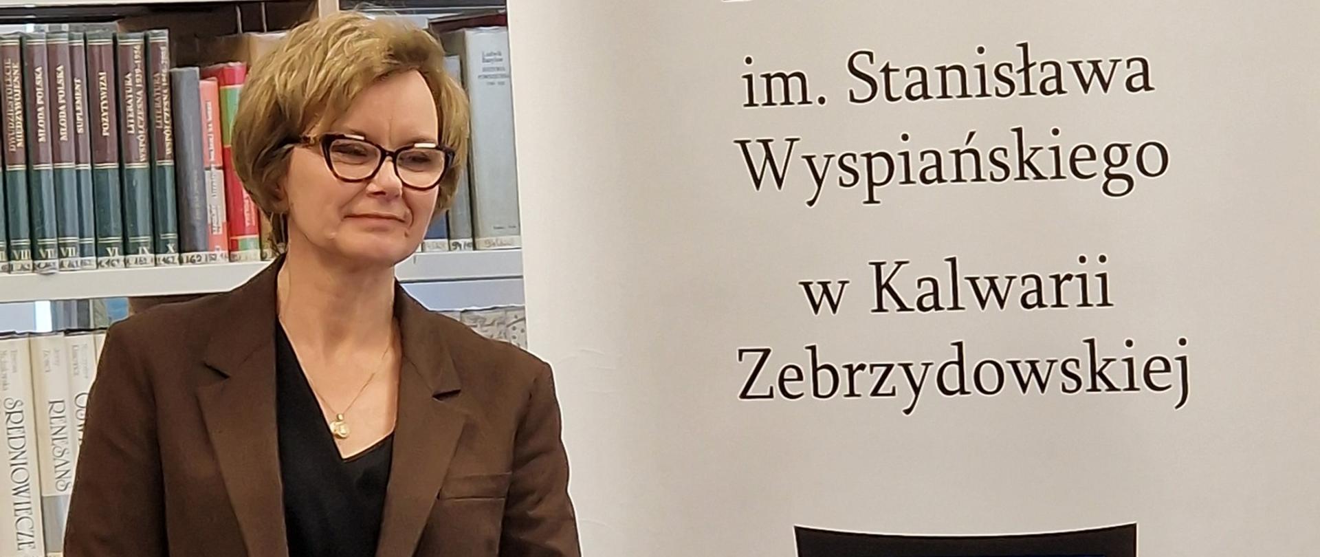 Stoi Jolanta Studnicka przed stolikiem z tomikami poezji 