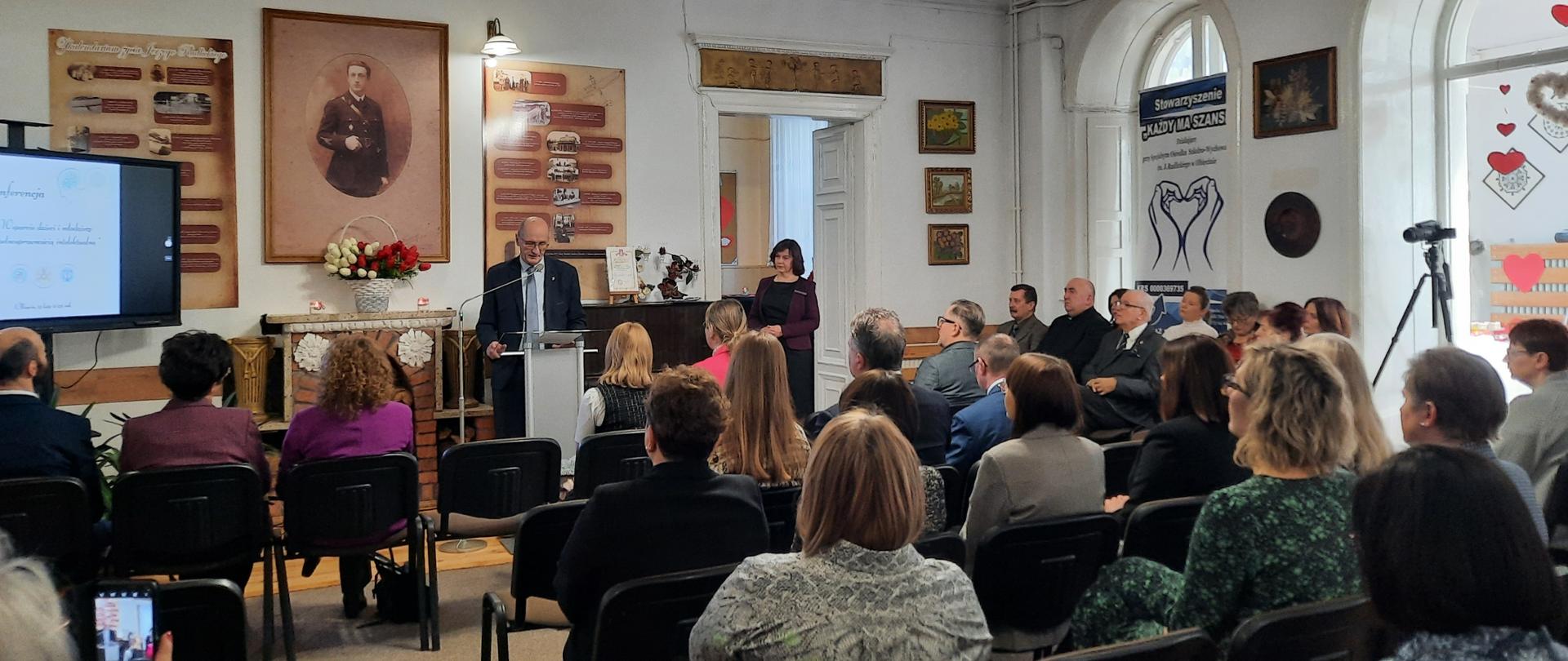 Na zdjęciu uczestnicy konferencji, którzy znajdują się w białej sali Specjalnego Ośrodka Szkolno-Wychowawczego w Olbięcinie. Na przeciw uczestników przy mównicy stoi Starosta Kraśnicki, który przemawia.