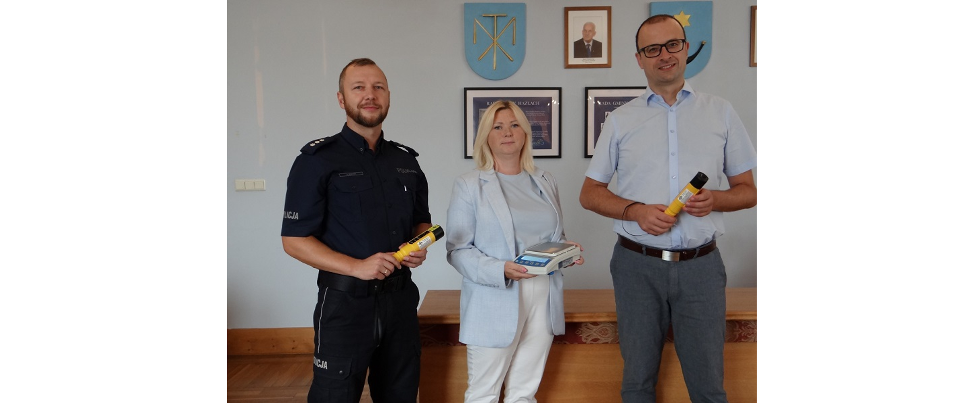 Przekazanie sprzętu w Urzędzie Gminy Hażlach z udziałem (od lewej): Komendanta Komisariatu kom. Tomasza Pochy, Zastępcy Wójta Renaty Żyły oraz Wójta Grzegorza Sikorskiego. Osoby na zdjęciu trzymają w ręku zakupione alkomaty oraz wagę
