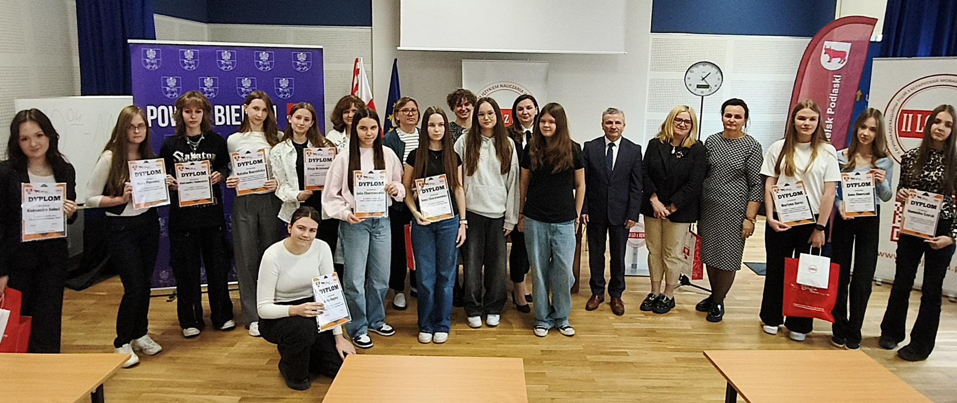 Uczestnicy konkursu "Mistrz Języka Polskiego 2025" wraz z dyrektorem II LO, nauczycielami i przedstawicielami Powiatu Bielskiego oraz Miasta Bielsk Podlaski