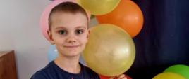 Chłopiec pozuje do zdjęcia przy balonach