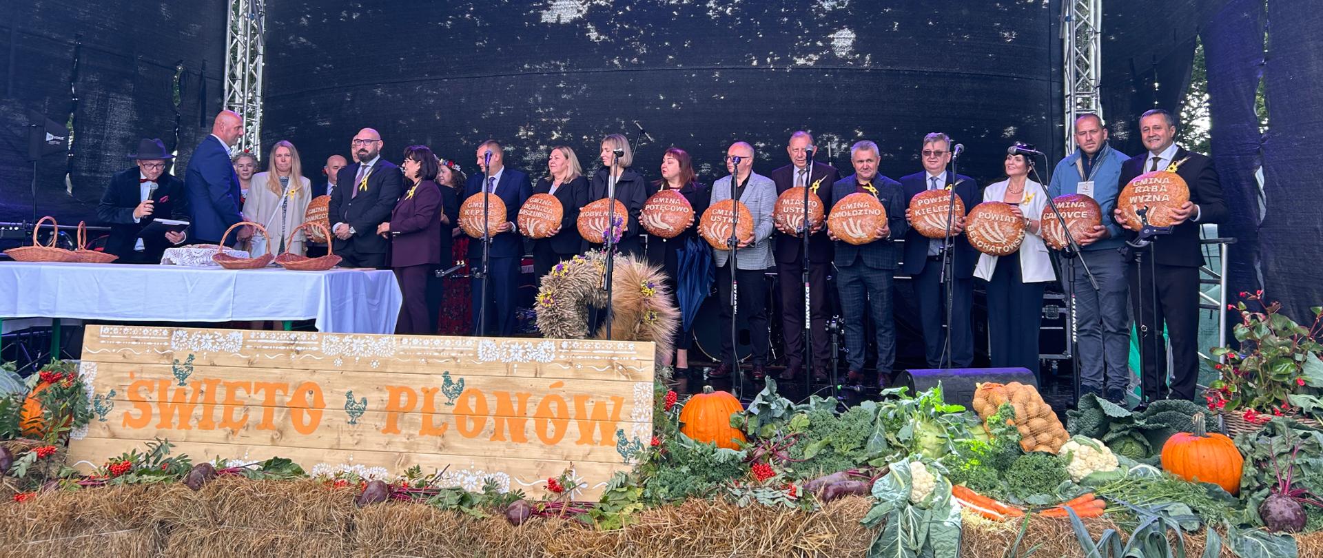 Przedstawiciele samorządów z chlebami dożynkowymi na scenie podczas Święta Plonów.