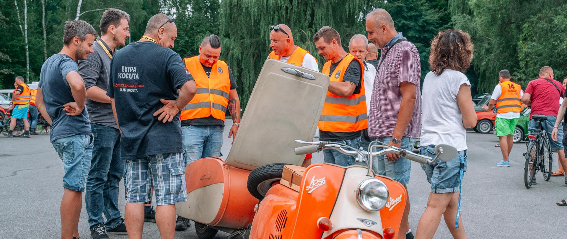 Mężczyźni oglądają stary motocykl.