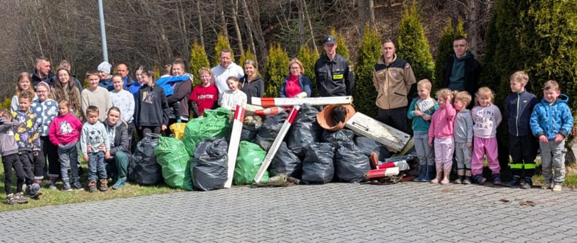 Grupa mieszkańców Bielanki po wydarzeniu zbierania śmieci na terenie miejscowości Bielanka przy workach ze śmieciami jakie nazbierali podczas akcji.
