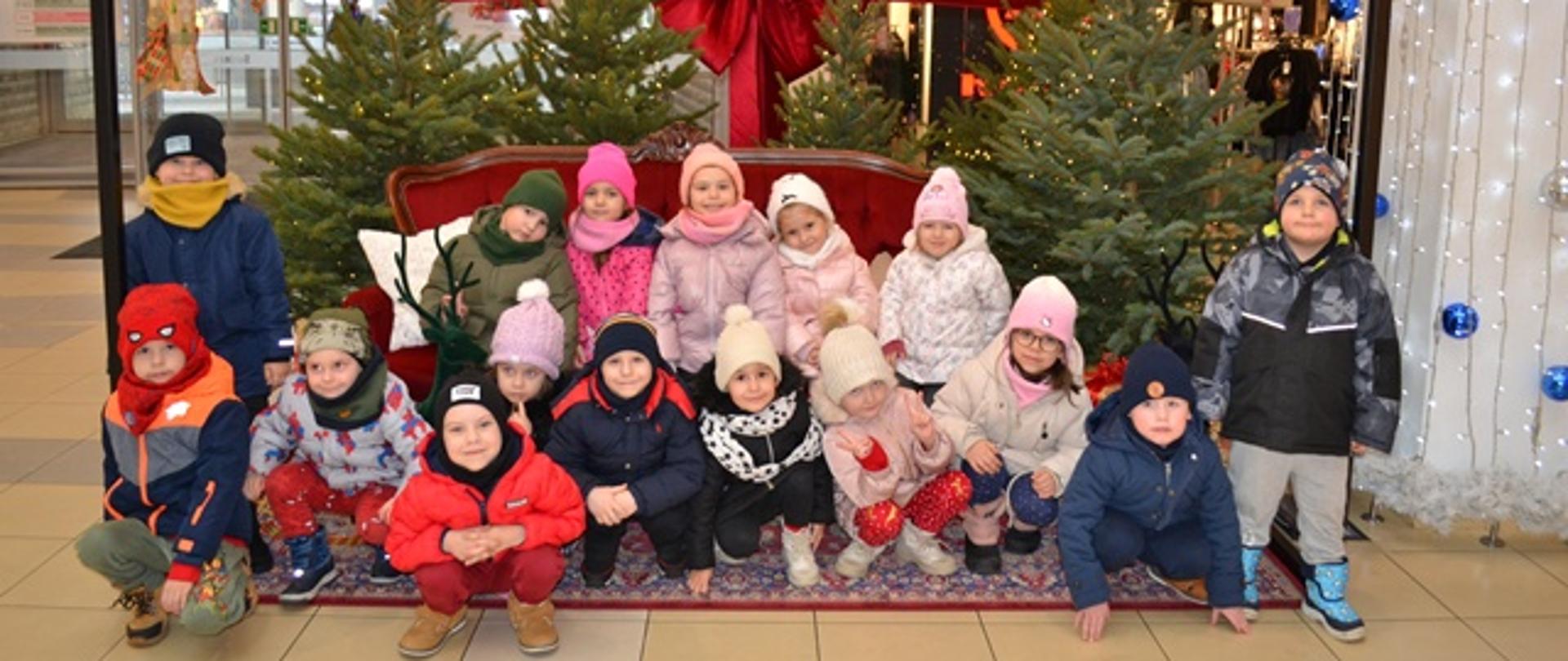 Dzieci pozują do zdjęcia na tle świątecznej ścianki
