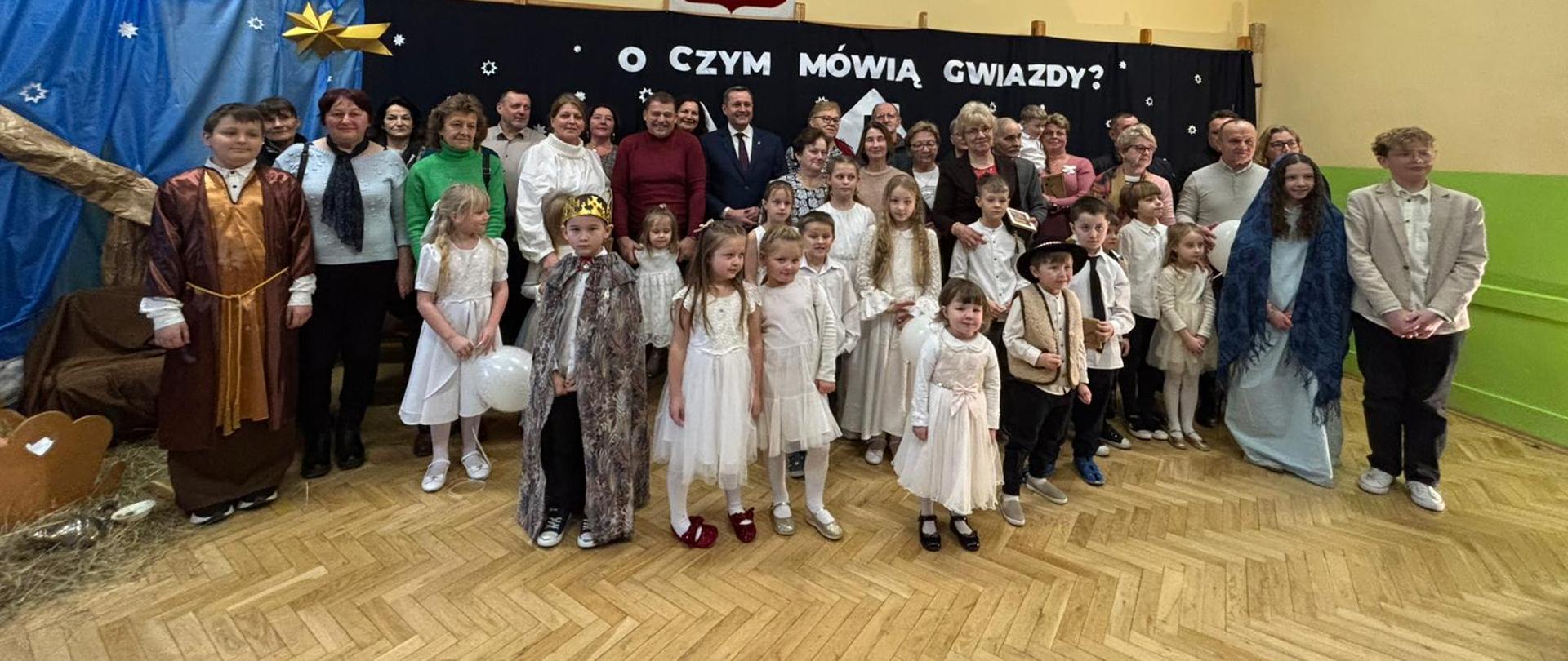 Dzień Babci i Dziadka 2026 w Szkole Podstawowej im. Mariusza Zaruskiego w Bielance. Na zdjęciu widoczni zaproszeni goście, uczniowie oraz Wójt Gminy Raba Wyżna. W tle napis "O czym mówią gwiazdy" oraz Godło Rzeczypospolitej Polskiej.