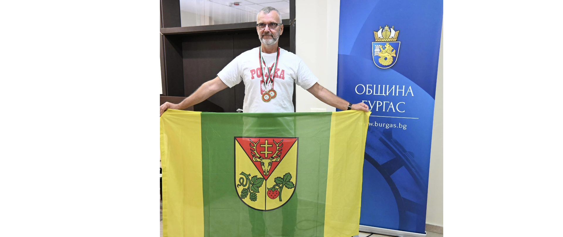 Mężczyzna z rozpostartymi rękami trzymający flagę Gminy Leżajsk