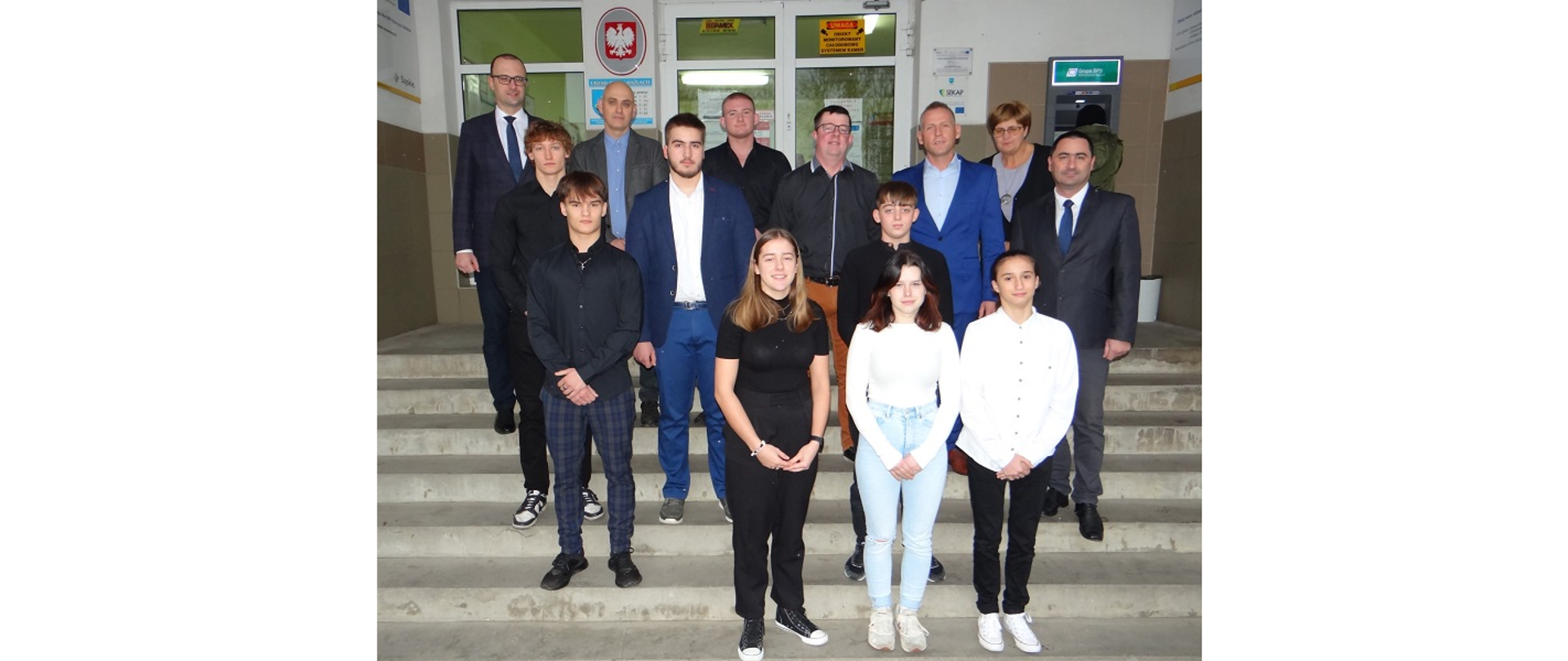 Wspólna fotografia najlepszych sportowców z władzami Gminy Hażlach. Osoby pozują do zdjęcia na schodach przed wejściem do budynku Urzędu Gminy
