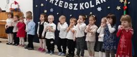 Przedszkolaki stoją w sali na tle ścianki "Pasowanie na przedszkolaka"