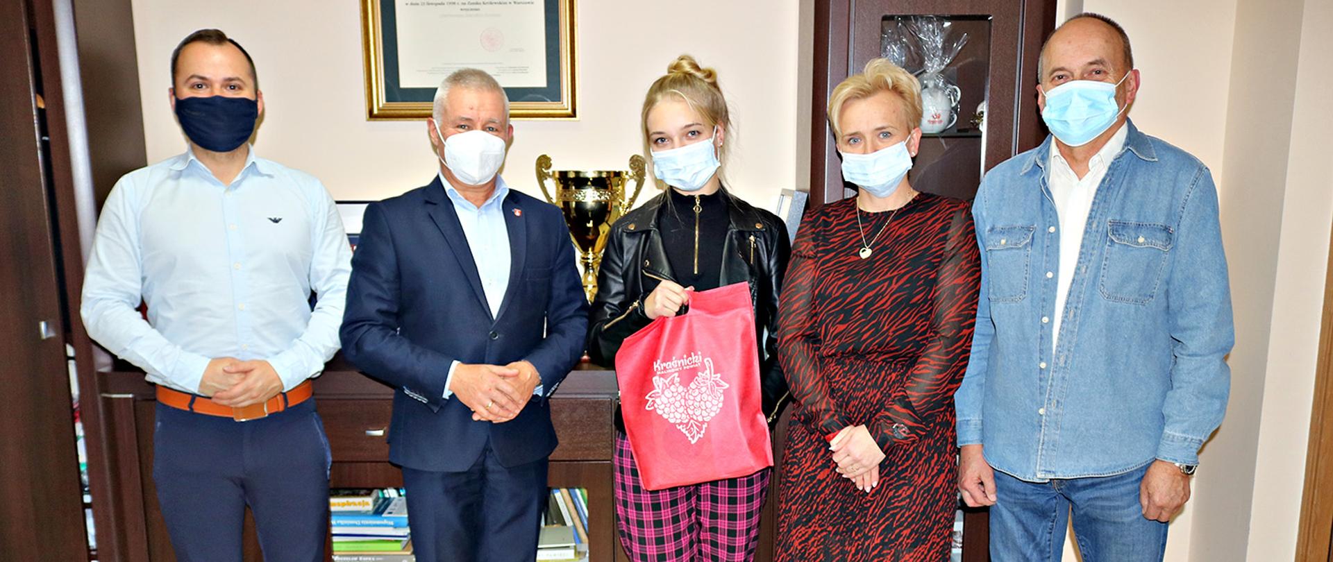 Od lewej strony Paweł Cieliczko - instruktor i trener wokalny artystki z Centrum Kultury i Promocji w Kraśniku, Starosta Kraśnicki Andrzej Rolla, Kinga Wołoszyn - młoda wokalistka, Urszula Wołoszyn - mama Kingi, pełniący obowiązki Kierownika Wydziału Promocji Andrzej Gotner. Uczestnicy spotkania pozują do zdjęcia. Kinga Wołoszyn trzyma w ręce torbę z upominkiem od starosty.