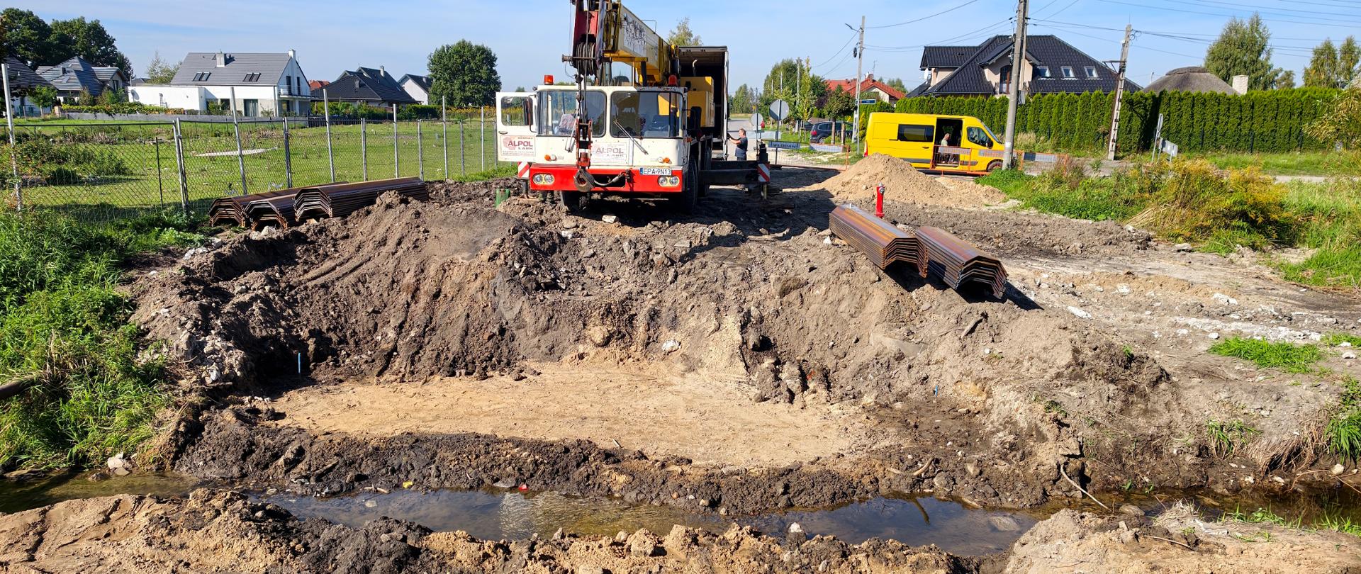 Trwają prace przy rozbudowie układu drogowego na ulicy Polnej. Na zdjęciu plac budowy, wykop oraz sprzęt wykorzystywany do przebudowy przepustu.