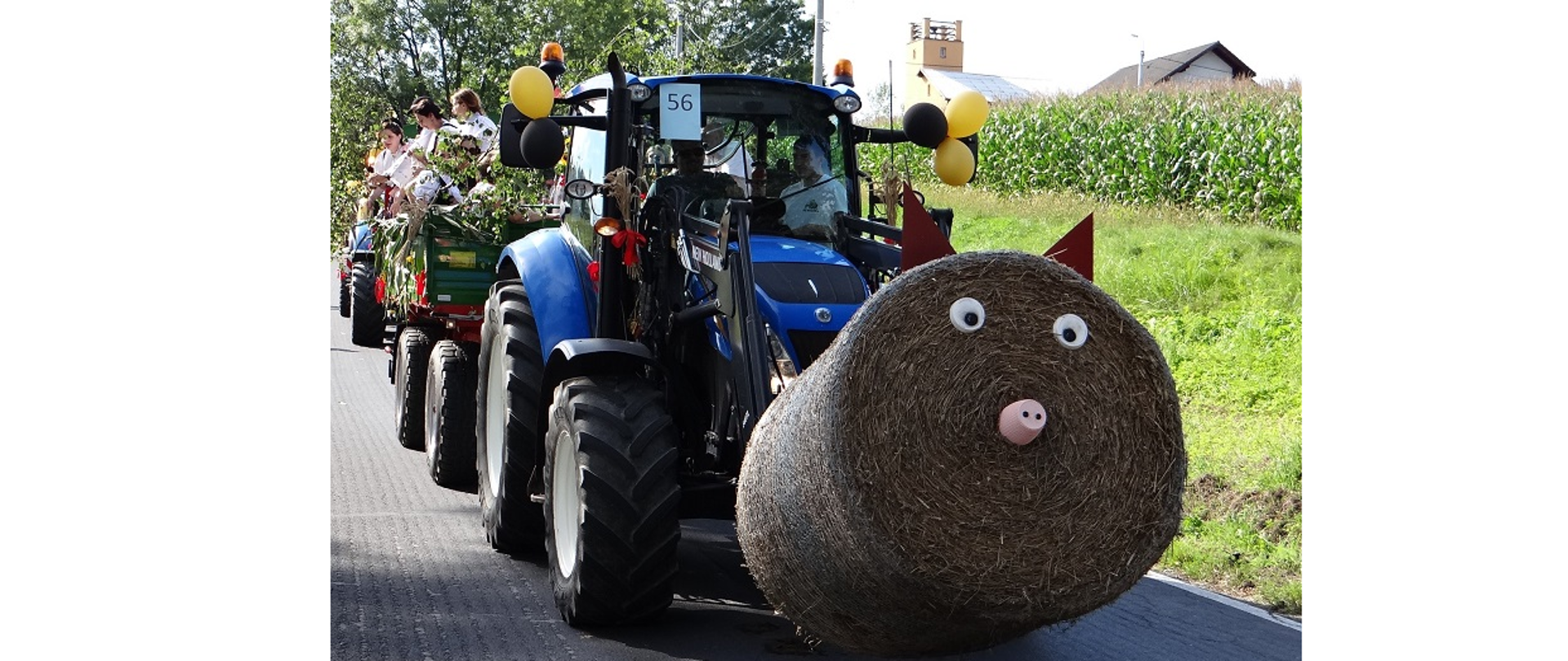 Dożynkowy korowód przejeżdża przez Hażlach. Na pierwszym planie fotografii widoczny barwie przystrojony ciągnik rolniczy z przyczepą 