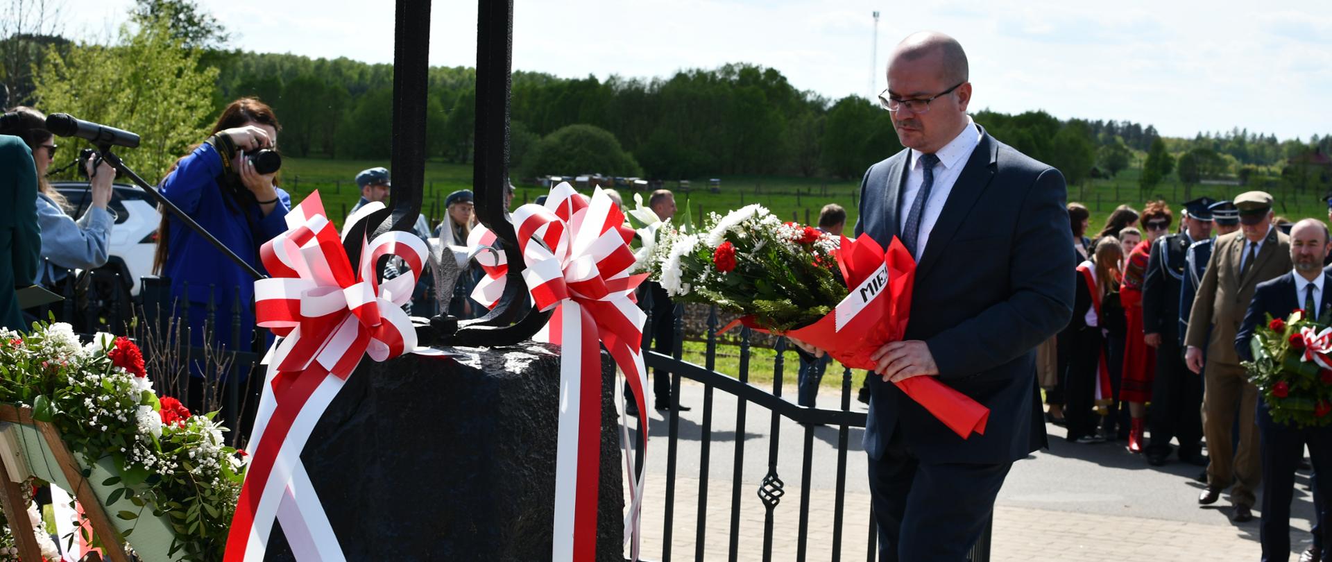 Sekretarz powiatu dr. Marek Martyniuk składa wiązankę podczas uroczystości 70. rocznicy buntu chłopskiego w Olendach
