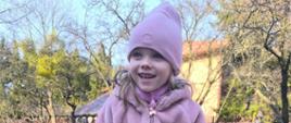 Dziewczynka pozuje do zdjęcia przy kwietniku
