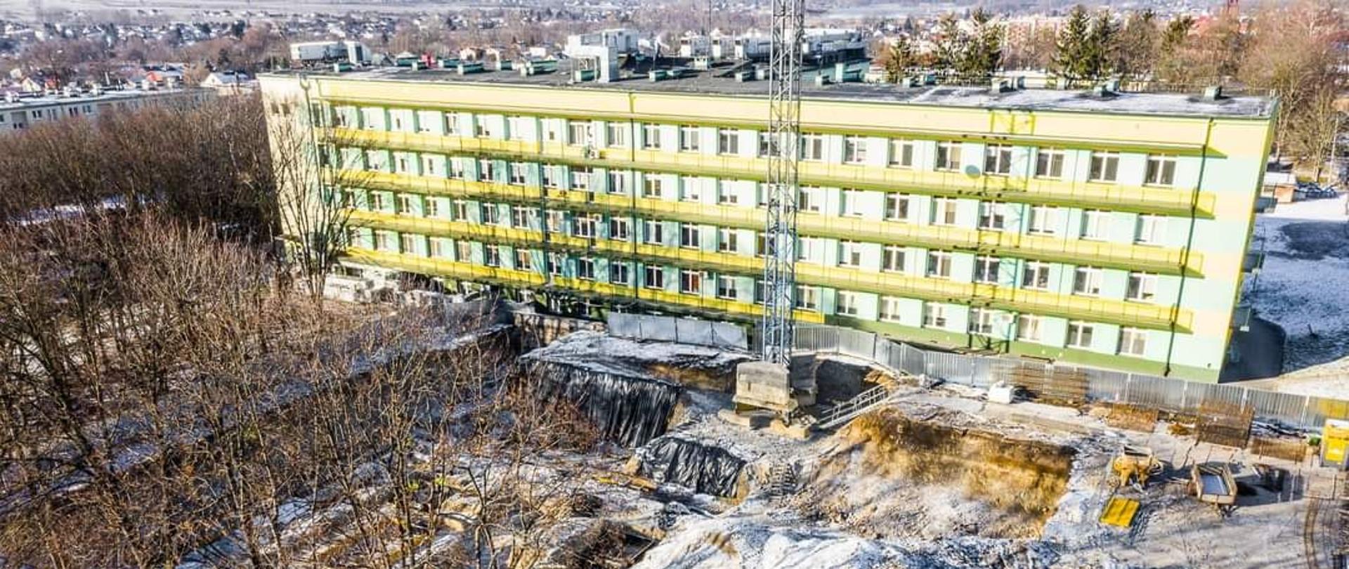 Na zdjęciu widać etap budowy nowego pawilonu Szpitala Powiatowego w Kraśniku, do którego przeniesiony zostanie Oddział Ginekologiczno-Położniczy oraz Oddział Neonatologiczny. Fotografia wykonana z góry przy użyciu drona z wysokości 30 metrów. W oddali widoczny jest Szpital Powiatowy w Kraśniku oraz panorama miasta Kraśnik.