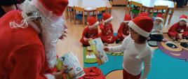 Mikołajki w przedszkolu - Mikołaj rozdaje dzieciom prezenty