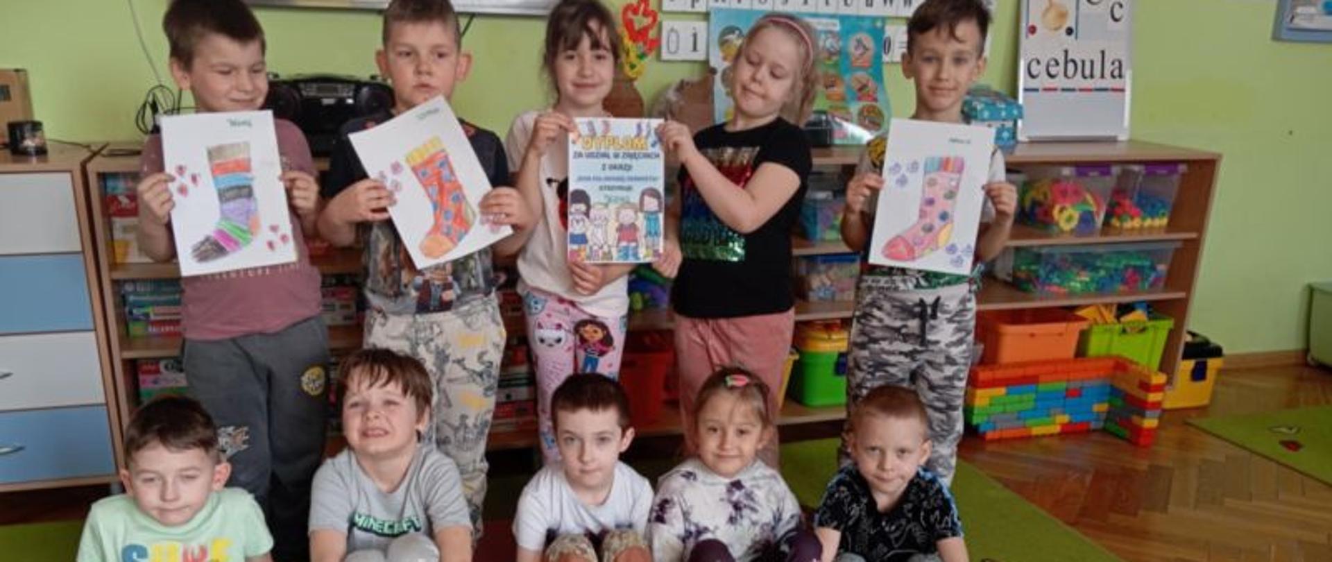 Dzieci prezentują na stopach kolorowe skarpety oraz rysunki przedstawiające tę część odzieży