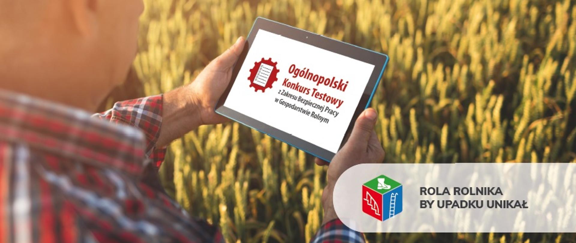 Mężczyzna trzyma tablet w rękach. Na nim widnieje napis Ogólnopolski Konkurs Testowy. Z prawej strony napis Rola rolnika by upadku unikał. W tle widać zborze