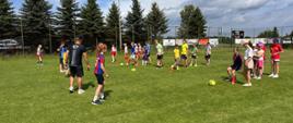 Dzieci na boisku sportowym grają w piłkę nożną.
