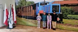 Przedszkolaki pozują do zdjęcia przy fototapecie kolejki wąskotorowej w budynku "Stacji"