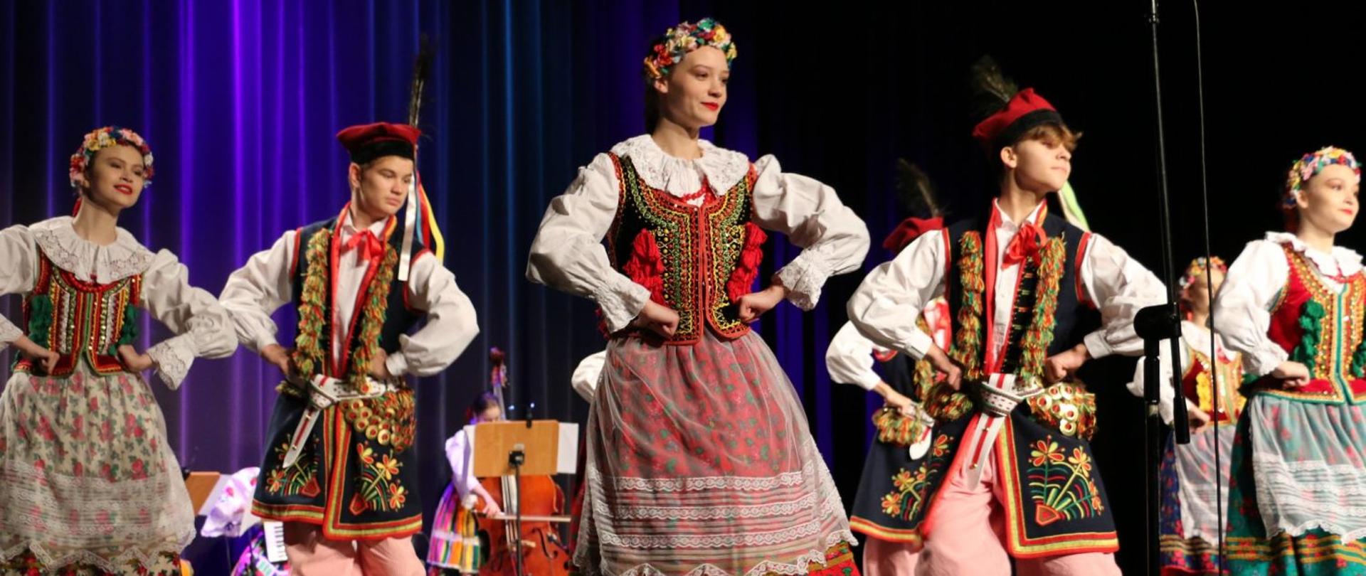 Zespół regionalny podczas występu na scenie, trzy kobiety i dwóch mężczyzn w regionalnych strojach.