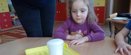 Pierwsze chemiczne doświadczenia - poznajemy świat! Dziewczynka patrz jak kubek wypełnia się pianą