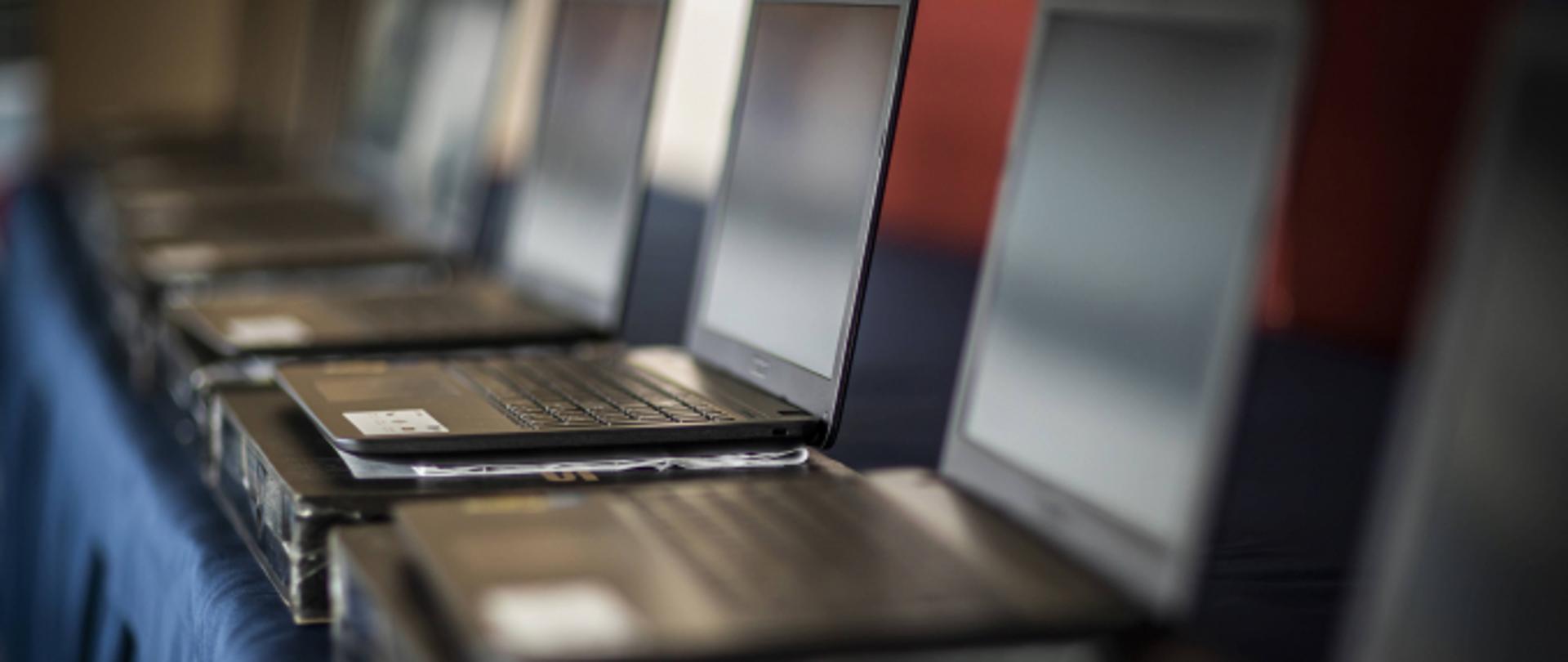 Na stoliku stoją czarne laptopy 