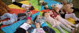 Wspólne zabawy podczas pikniku - dzieci leżą na kolorowej macie