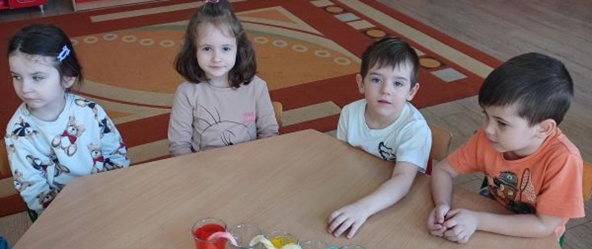 Pierwsze chemiczne doświadczenia - poznajemy świat! Dzieci siedzą przy stole, a przed nimi szklanki z kolorową cieczą