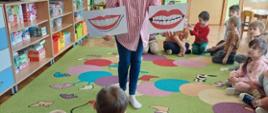 Prowadząca zajęcia prezentuje dzieciom plansze przedstawiające wady zgryzu
