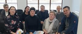 uczestnicy spotkania edukacyjnego w Sieniawie siedzą na krzesłach, krzesła ustawione w dwóch rzędach jeden za drugim w tle widać duże okna. 
