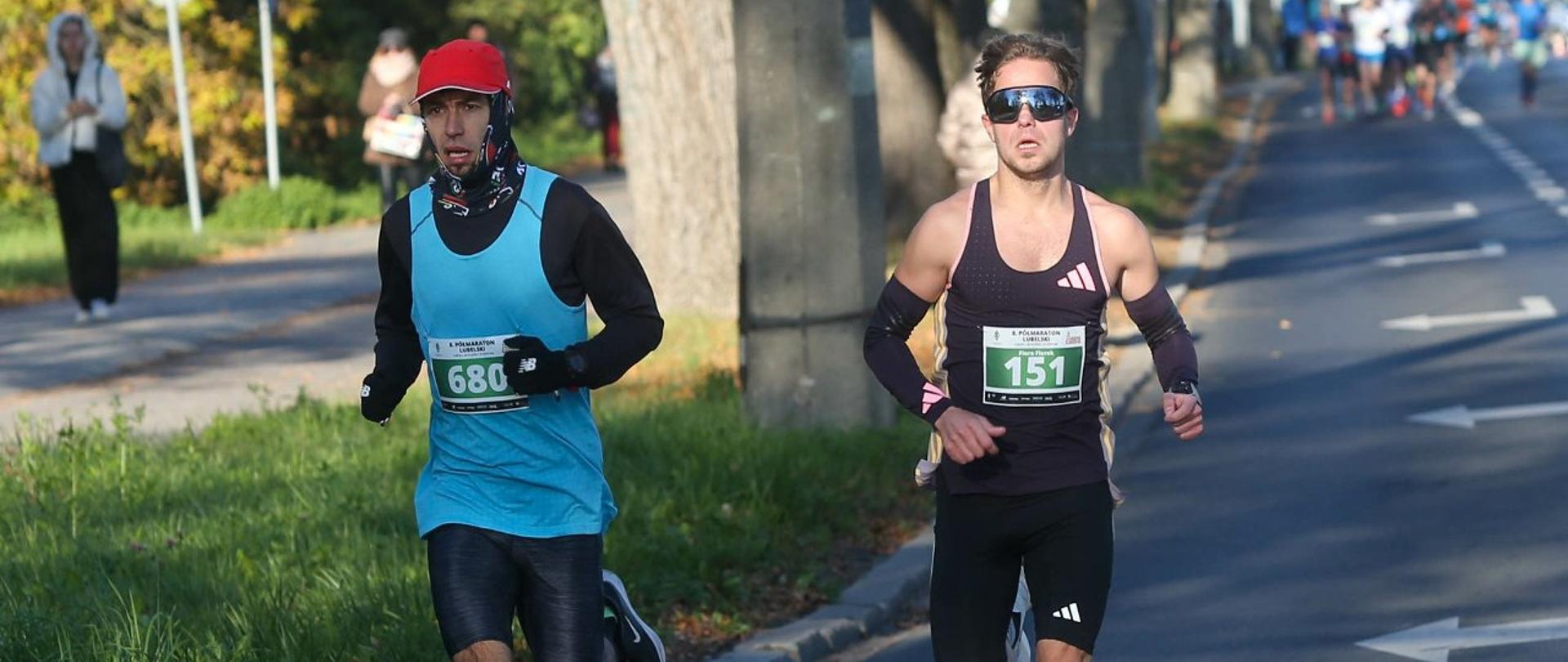 Michał Biały na trasie półmaratonu. Obok, z jego prawej strony, biegnie inny zawodnik.