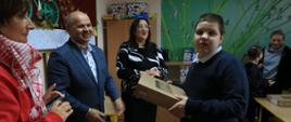 Zdjęcie przedstawia Wicestarostę Kraśnickiego Andrzeja Misztala oraz Dyrektora Zespołu Szkół Specjalnych w Kraśniku Annę Niekrę wręczających laptop uczniowi.