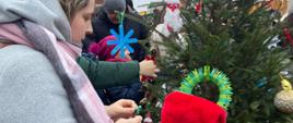 Dzieci z pomocą rodziców ubierają choinkę na Jarmarku