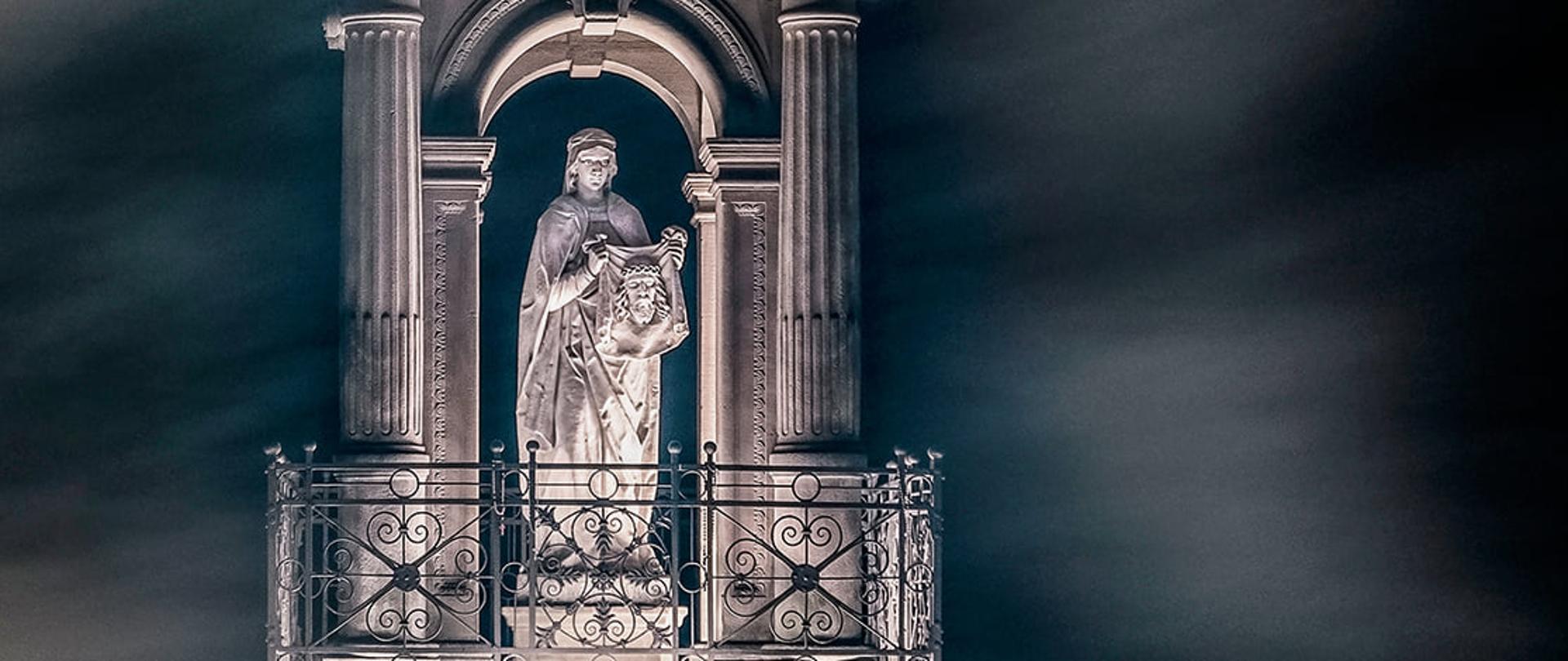 Plakat wystawy Calvaria Mystica. Dominujący element plakatu to nocna fotografia kaplicy św. Weroniki, oświetlona świecami rozmieszczonymi dookoła niej. Pozostałą część plakatu zajmują informacje o wydarzeniu i logotypy organizatorów.