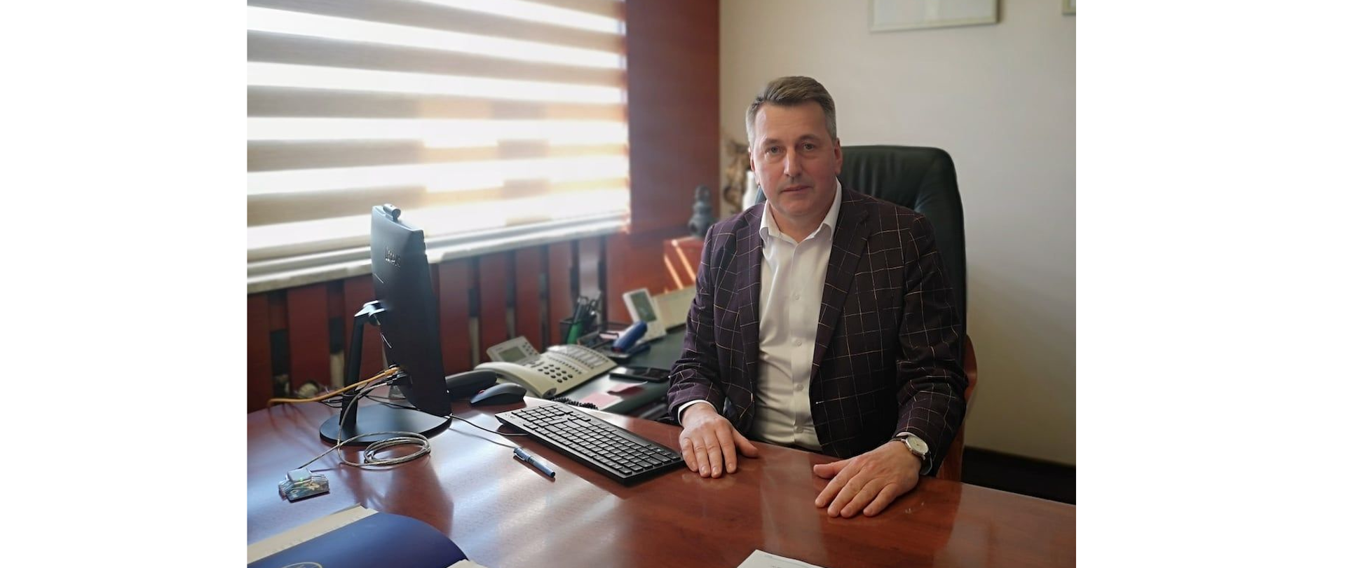 Na zdjęciu znajduje się mężczyzna siedzący przy biurku
