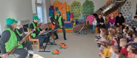 Artyści, którzy odwiedzili przedszkole. Siedzą przed dziećmi z instrumentami