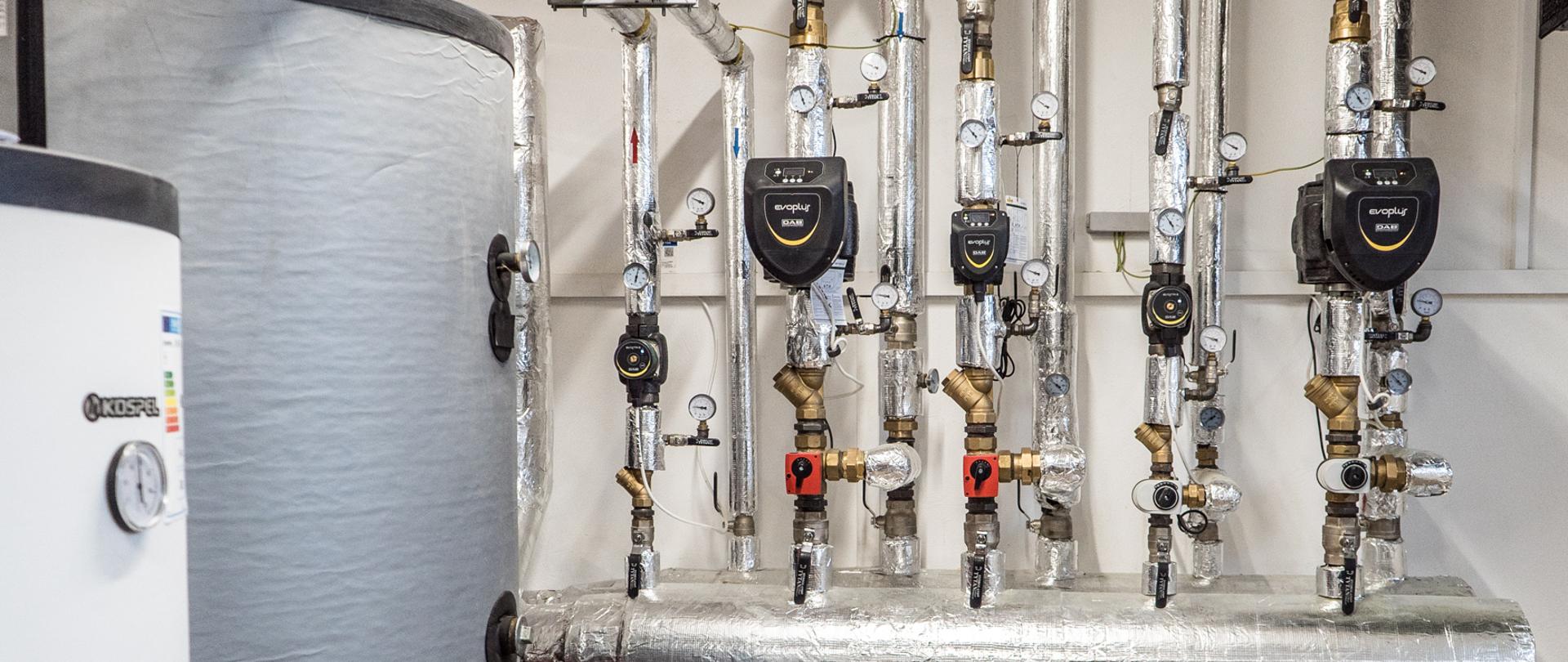 Na zdjęciu widoczne pompy oraz zawory z lewej strony bojler szary oraz bardziej z przodu bojler biały.