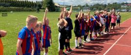 Uczestnicy turnieju 1'1 na boisku sportowym ustawieni w linii.