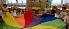 Zabawy w grupie 3latków - dzieci w sali trzymają kolorową płachtę w kształcie koła