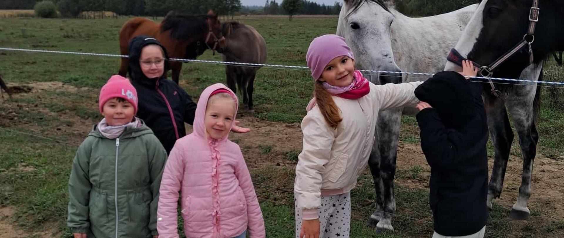 Zabawy w stadninie - trzy dziewczynki głaszczą konia