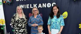 Pani Dyrektor oraz nauczycielki zaangażowane w organizację konkursu, pozują do zdjęcia wraz z nagrodzonym uczestnikiem