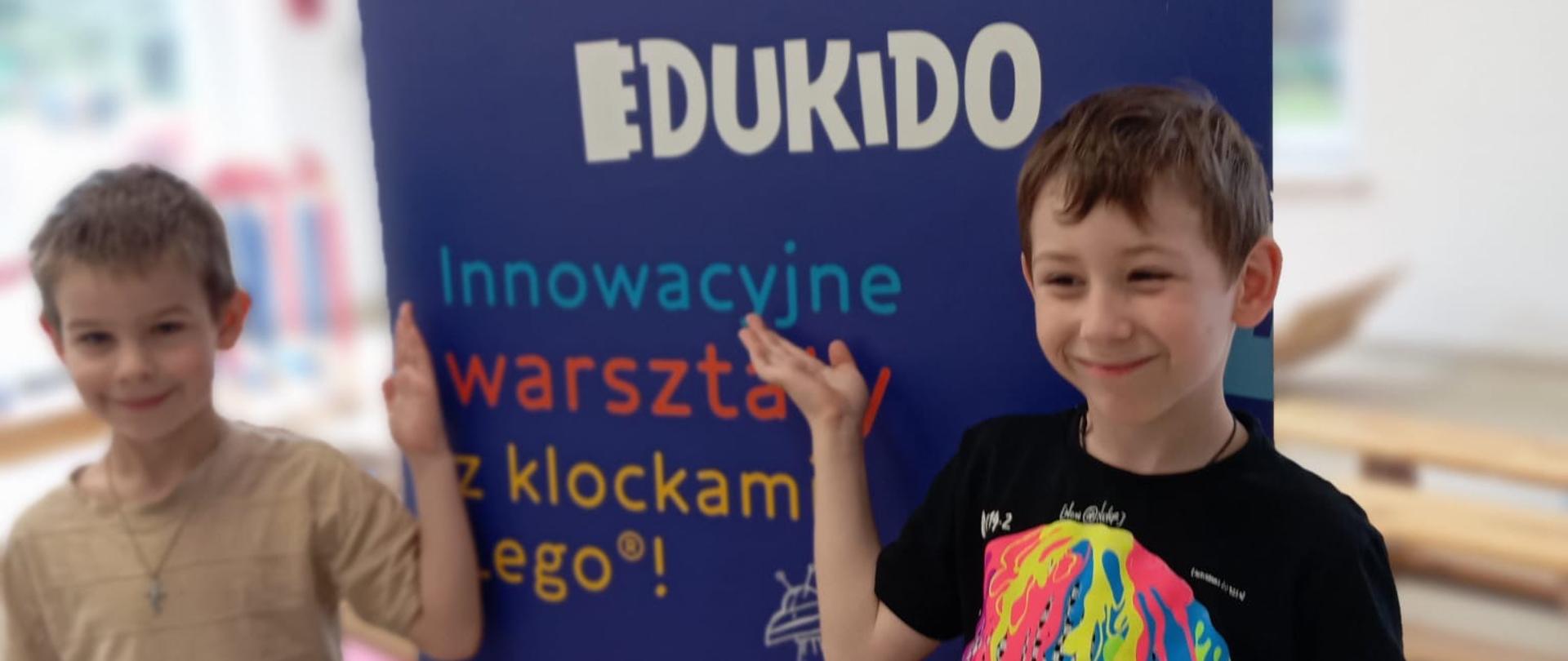 Dwóch chłopców stoi przy banerze promującym Edukido