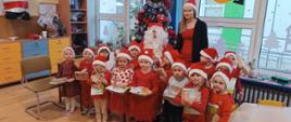 Mikołajki w przedszkolu - dzieci, nauczycielka i mężczyzna przebrany za św. Mikołaja pozują do zdjęć